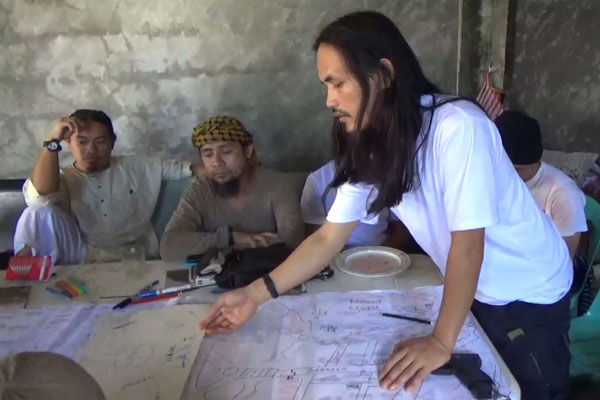  Gambar fail tidak bertarikh daripada video serahan tentera Filipina pada 18 Jun lalu menunjukkan Hapilon (tengah) dan Abdullah Maute (kanan), adik lelaki Maute yang juga pengasas bersama kumpulan Maute, ketika mereka merancang serangan di satu lokasi tidak didedahkan di pulau Mindanao. — Gambar AFP