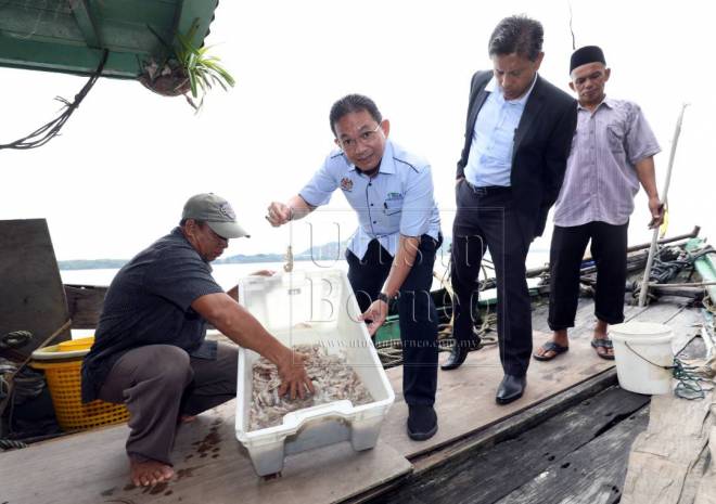 Irmohizam (dua kiri) ketika menyaksikan pemunggahan hasil tangkapan nelayan yang telah mula mendaratkan hasil laut di kompleks pelabuhan Tanjong Bako, semasa lawatan beliau, pagi tadi