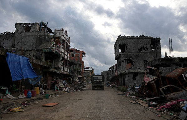  Trak tentera melintasi bangunan yang musnah akibat perang di bandar Bangolo, Marawi City kelmarin. — Gambar Reuters