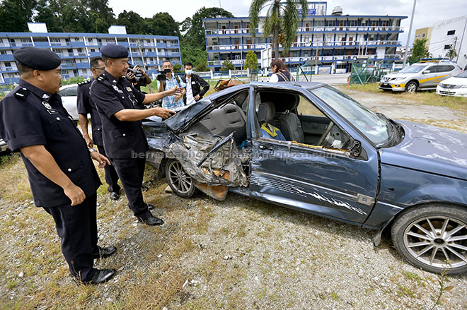  Supt Som (dua kiri) menunjukkan kereta Proton Iswara yang turut terlibat dalam kes kemalangan di antara sebuah lori membawa ais dan van yang meragut sembilan nyawa di Mambang Di Awan dekat Kampar Sabtu lalu. — Gambar Bernama