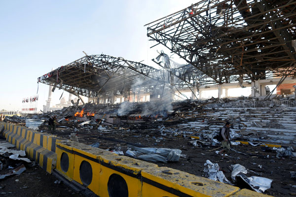  Seorang wartawan (kanan) dan para pejuang Huthi memeriksa tempat kejadian serangan udara di dataran perarakan di Sanaa, kelmarin. — Gambar Reuters