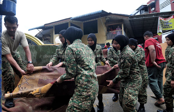  Anggota Askar Wataniah membuang tikar surau yang musnah akibat banjir kelmarin di Taman Penang Free School semalam. — Gambar Bernama