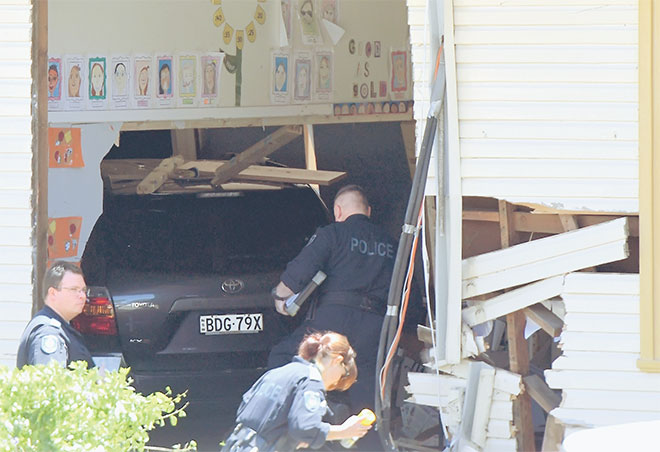  Pegawai perkhidmatan kecemasan dan polis memeriksa sebuah kenderaan yang merempuh bilik kelas sebuah sekolah rendah di Greenacre, pinggir Sydney semalam. — Gambar Reuters