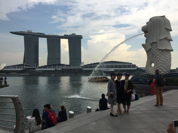  Pelancong merakam kenangan berlatarbelakangkan              Merlion dan Marina Bay Sands.