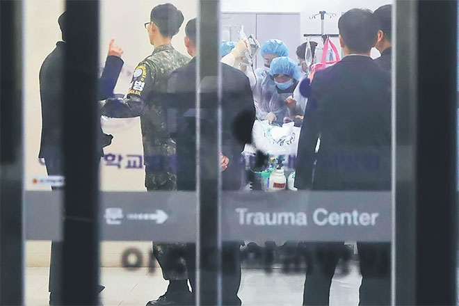  Seorang pegawai tentera Korea Selatan (dua kiri) memerhatikan anggota perubatan merawat seseorang yang dipercayai askar Utara yang berpaling tadah, di sebuah hospital di Suwon, selatan Seoul kelmarin. — Gambar AFP