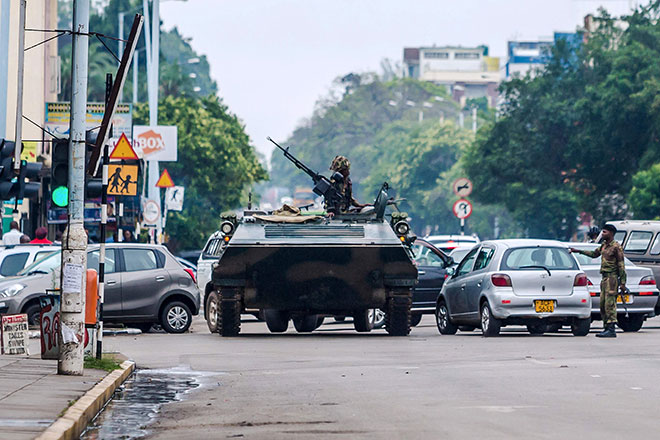 DIGULINGKAN?: Kereta perisai berkawal di persimpangan jalan di Harare kelmarin ketika Mugabe (sisipan) mendakwa beliau                    di bawah tahanan rumah meskipun golongan jeneral menafikan mereka melancarkan kudeta. — Gambar AFP/Reuters