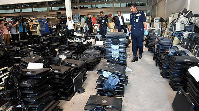  Ramli (kanan) meneliti peralatan elektronik yang dilupuskan selepas sidang media tentang pelupusan barang kes di Ibu Pejabat Polis Kepayan, Kota Kinabalu semalam. — Gambar Bernama