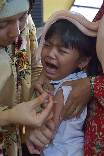  Seorang kanak-kanak perempuan menangis ketika disuntik dengan vaksin difteria di sebuah klinik kampung di Jakarta, semalam. — Gambar AFP