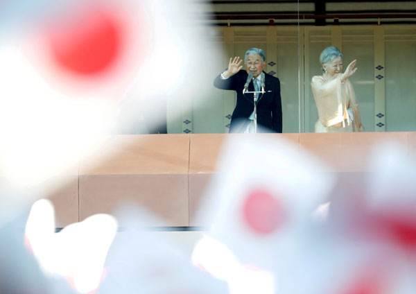  Akihito bersama Maharani Michiko melambai ke arah rakyat jelata yang mengibar bendera Jepun selepas baginda menyampaikan ucapan tradisional Tahun Baharu di Istana Maharaja di Tokyo, semalam. — Gambar AFP