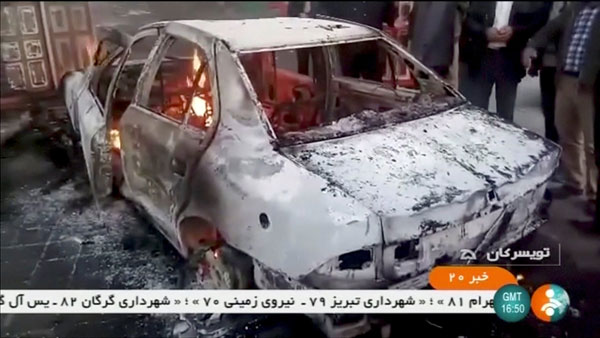  Orang ramai melihat sebuah kereta terbakar di Tuyserkan, wilayah Hamadan, Iran                   dalam gambar pegun diambil daripada video pada 31 Disember 2017. — Gambar IRINN/Reuters