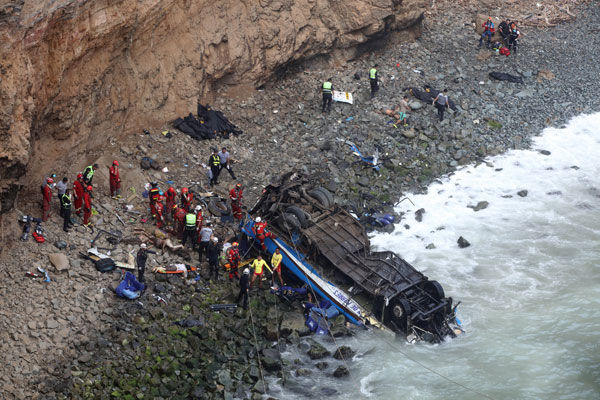  Anggota penyelamat menjalankan tugas mereka di mana sebuah bas mendarat dalam keadaan terbalik di atas batu selepas berlanggar dengan trak dan terjunam di tebing curam tepi laut di lebuh raya utara Lima, Peru, kelmarin. — Gambar Reuters