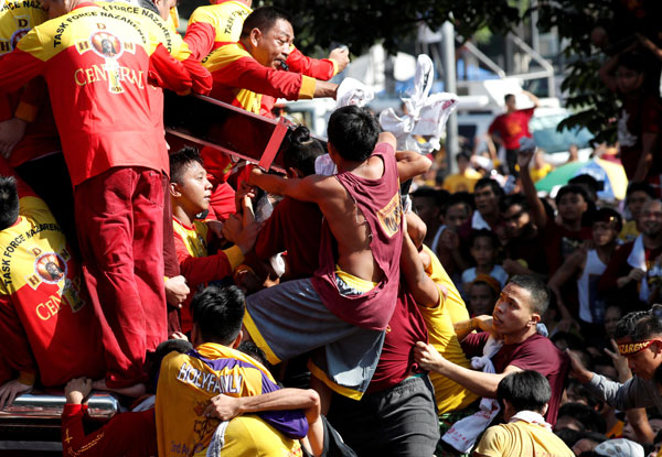  Para penganut berpaut pada salib yang membawa imej Black Nazarene semasa perarakan tahunan Roman Katolik di Manila, semalam. — Gambar Reuters