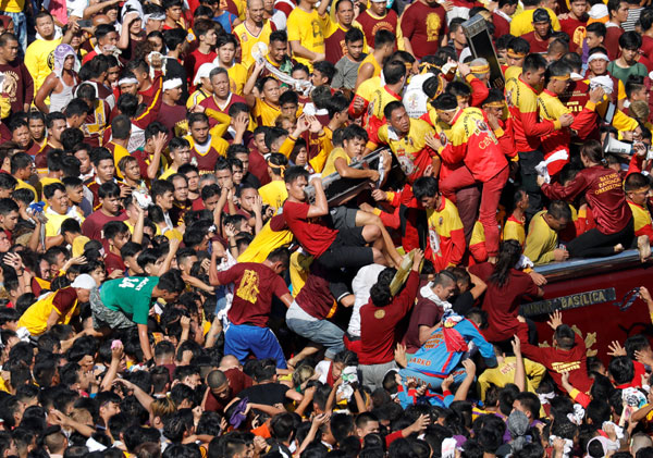  Penganut Katolik berebut memanjat ke atas pedati yang membawa imej ‘Black Nazarene’ ketika jutaan mengambil                     bahagian dalam perarakan tahunan agama tersebut di Chinatown, Metro Manila, kelmarin. — Gambar Reuters