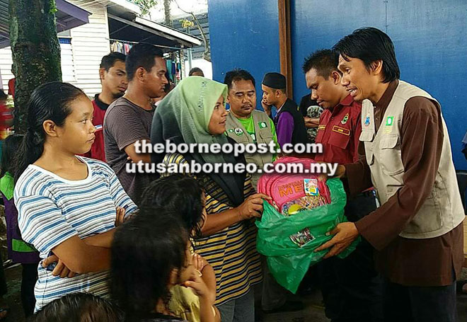  Sahar (kanan) menyampaikan bantuan kepada mangsa kebakaran di Kampung Sundang Laut, Sandakan.