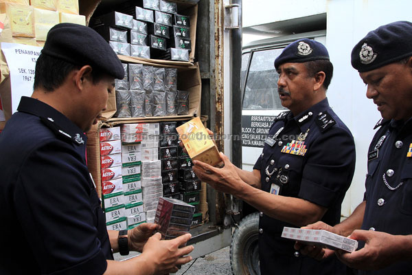  Razarudin  (tengah) memeriksa rokok yang dirampas selepas mengadakan sidang media di Ibu Pejabat Polis Daerah Penampang semalam. — Gambar Bernama 