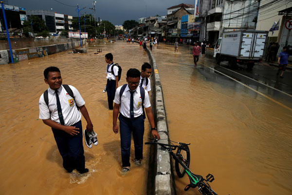  Pelajar meredah jalan yang dilanda banjir ketika dalam perjalanan ke sekolah di Jakarta, Indonesia semalam. — Gambar Reuters