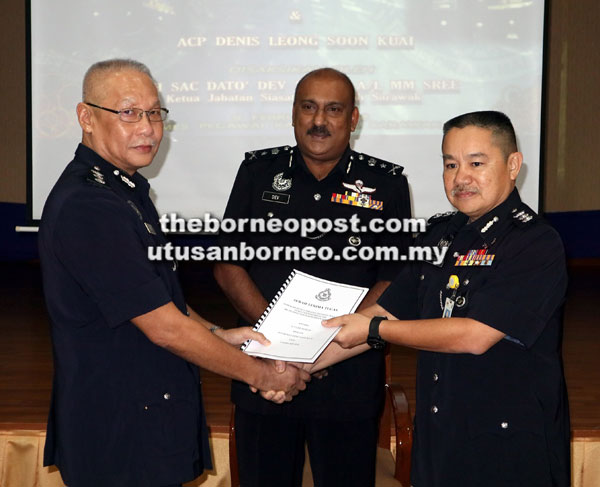  Dev (tengah) menyaksikan Lee (kiri) menyerahkan dokumen penyerahan tugas kepada Leong di IPK Sarawak, semalam.