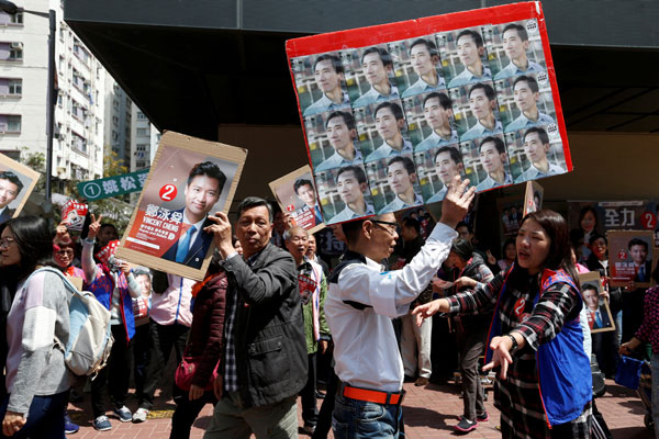  Seorang penyokong membawa gambar Yu melintasi penyokong Cheng semasa pilihan raya kecil di Hong Kong, semalam. — Gambar Reuters