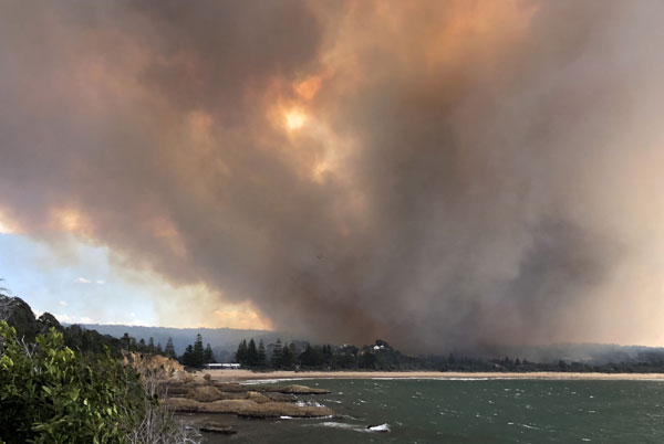  Gambar yang dirakam kelmarin dan diserahkan semalam oleh David Porter menunjukkan asap berkepul dari kawasan yang terbakar di kampung Tathra, pantai selatan New South Wales. — Gambar AFP