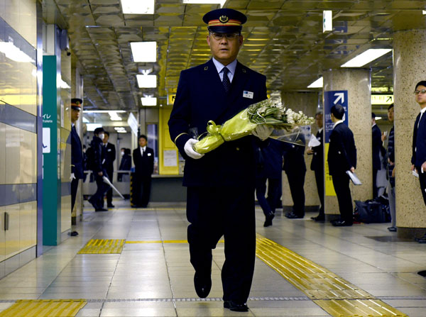  Pengurus stesen kecil Kasumigaseki Toyohiko Otomo membawa jambangan bunga untuk diletakkan di atas astaka peringatan mangsa serangan gas sarin 1995 di stesen berkenaan di Tokyo, semalam. — Gambar AFP