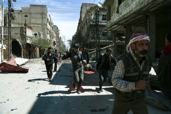  Anggota Pertahanan Awam Syria yang dikenali sebagai ‘White Helmets’ mengusung seorang lelaki yang cedera untuk menerima rawatan susulan serangan udara ke atas Douma, bandar utama Ghouta Timur kelmarin. — Gambar AFP