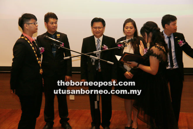  Lau mengangkat sumpah sebagai presiden baharu JCI Belia UCTS 2018 sambil disaksikan oleh Chieng (tiga kiri) serta yang lain.