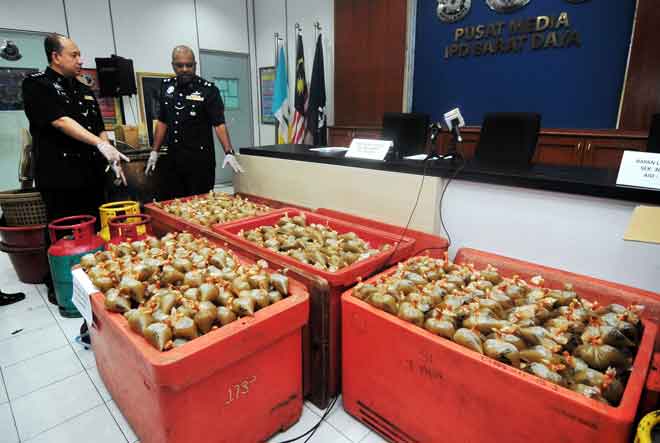  A. Anbalagan (dua kiri) menunjukkan bungkusan ketum serta peralatan memproses ketum bernilai RM13,000 ketika sidang media di Ibu Pejabat Polis Daerah Barat Daya dekat Balik Pulau, semalam. — Gambar Bernama