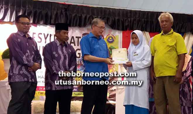  Fadillah (tiga kiri) menyampaikan insentif kepada salah seorang pelajar cemerlang SMK Semerah Padi di Kuching semalam. 