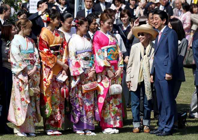  Abe (kanan) beramah mesra dengan kumpulan penyanyi K-pop ‘E-girls’ yang memakai         pakaian tradisional kimono semasa majlis menyaksikan bunga ceri mekar di taman Shinjuku Gyoen di Tokyo, Jepun semalam. — Gambar Reuters