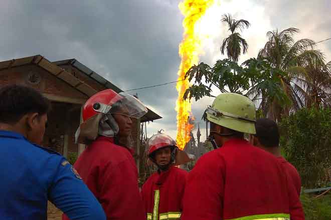  Anggota bomba dilihat berkumpul dekat telaga minyak haram yang terbakar di Peureulak, di wilayah Aceh, Indonesia semalam. — Gambar AFP