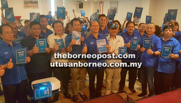 WILFRED (tengah) bersama Majlis Tertinggi UPKO merakam gambar kenangan sambil menunjukkan buku manifesto UPKO yang diedar pada majlis berkenaan.