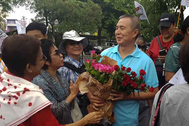  Somyot menerima bunga ros daripada penyokong yang menyambut pembebasannya              di luar penjara Bangkok di Thailand semalam. — Gambar Reuters