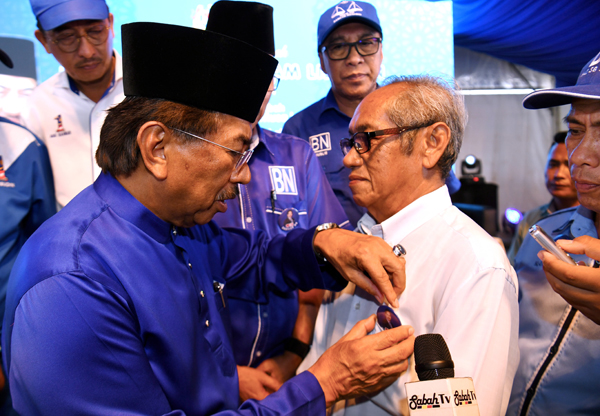 MUSA (kiri) yang juga calon BN Dewan Undangan Negeri Sungai Sibuga menyematkan lencana di baju Ketua Bahagian Parti Harapan Rakyat Sabah Parlimen Batu Sapi Basri Ibrahim yang mengumumkan memihak kepada BN selepas majlis pecah tanah Kompleks Pusat Islam di Jalan Sungai Kayu hari ini.