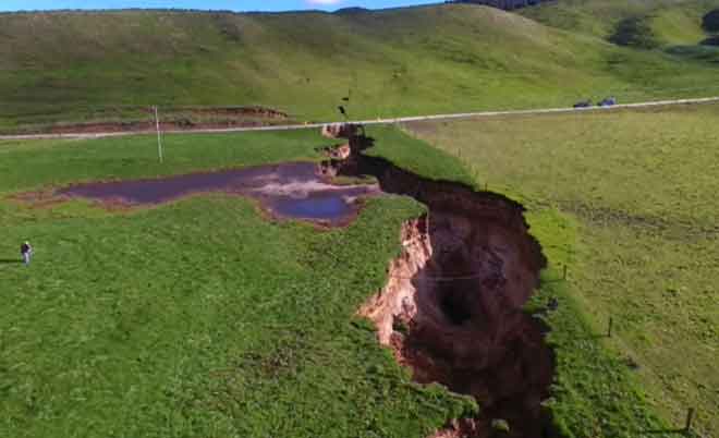  Imej daripada video TVNZ dirakam pada 2 Mei menunjukkan lubang benam yang muncul di ladang tenusu berhampiran pekan Rotorua di North Island, New Zealand. — Gambar AFP