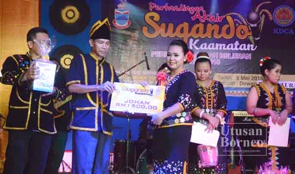 JANAI Sikana menyampaikan hadiah juara Pertandingan Sugandoi Kaamatan     Beluran 2018 kepada Jovinia Umjin bagi mewakili Pegawai Daerah Beluran.