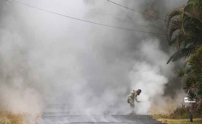  Seorang pegawai dilihat mengukur paras gas sulfur dioksida di kawasan kejiranan Leilani Estates selepas letusan gunung berapi Kilauea di Big Island, Hawaii kelmarin. — Gambar AFP