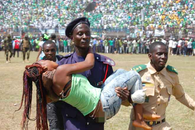  Seorang wanita yang cedera dalam rempuhan itu dibawa anggota polis ke tempat selamat semasa majlis angkat sumpah Bio di Freetown, kelmarin. — Gambar AFP