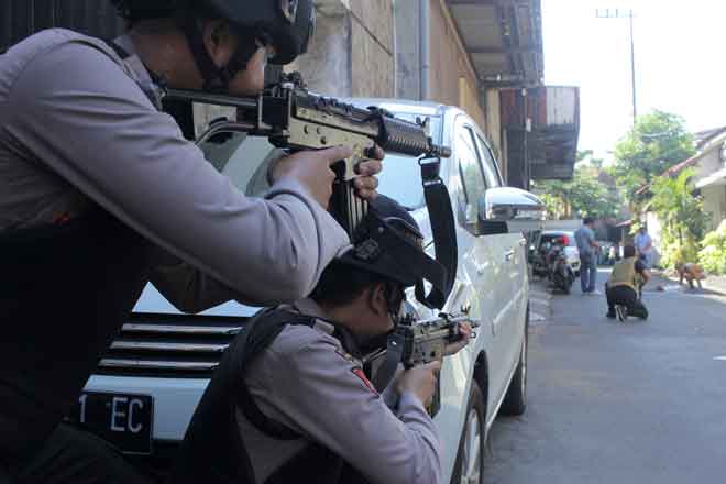  Gambar serahan Antara Foto yang dirakam Didik Suhartono menunjukkan polis                 mengacu senapang ke arah seorang lelaki yang sedang diperiksa anggota polis lain selepas letupan bom nekad di ibu pejabat polis yang berhampiran di Surabaya, Indonesia, semalam. — Gambar Reuters