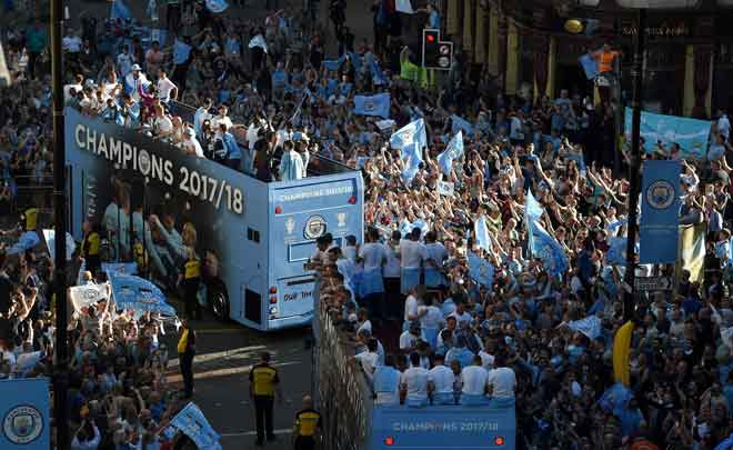  Para pemain dan pegawai pasukan menaiki bas terbuka disambut oleh ribuan para penyokong City yang membanjiri di jalan-jalan di kota Manchester untuk meraikan kejayaan mereka menjuarai Liga Perdana Inggeris. — Gambar Reuters