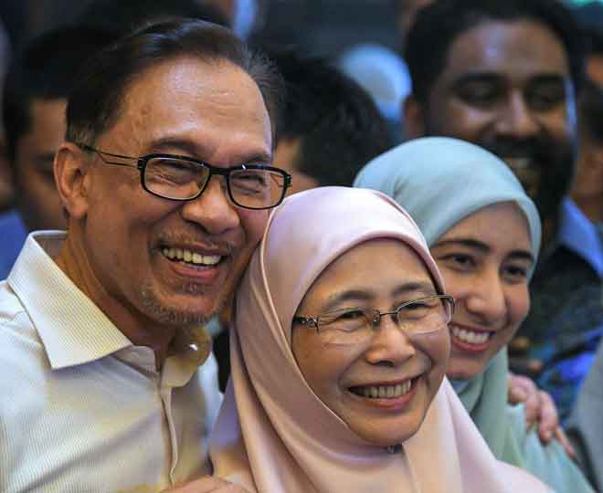  Anwar bergambar bersama isterinya Wan Azizah selepas sidang media di pekarangan rumahnya di Segambut semalam, setelah dibebaskan apabila menerima pengampunan penuh daripada Yang di-Pertuan Agong Sultan Muhammad V. Turut sama anaknya, Nurul Ilham Anwar (kanan). — Gambar Bernama