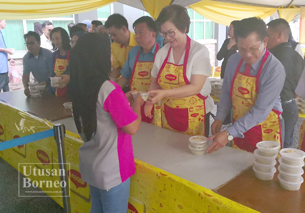 CHRISTINA (dua kanan) mengagihkan bubur lambuk kepada salah seorang pengunjung.