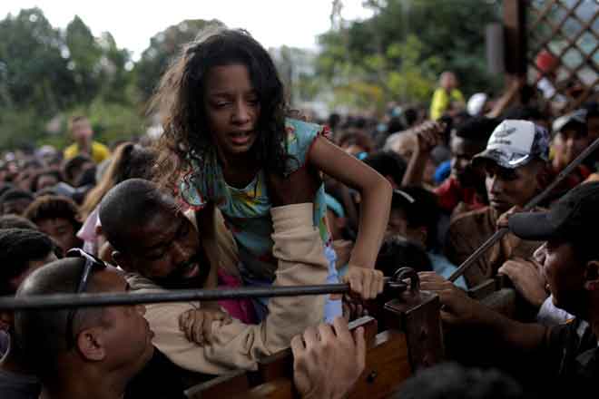  Seorang kanak-kanak perempuan cuba memanjat masuk ke dalam pusat latihan tempat pasukan Brazil berlatih di Rio de Janeiro, Brazil. — Gambar Reuters