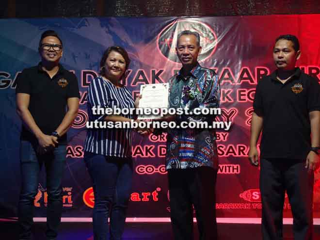  Penguang menyampaikan sijil penghargaan kepada salah seorang penerima terlibat menjayakan Gawai Dayak Bazaar 2018 sambil disaksikan oleh Vicky (kiri) dan Ganda di Miri kelmarin.