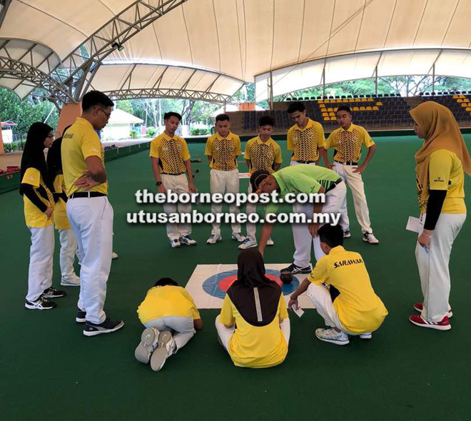  Zuraidi (tunduk) memberi tips kepada atlet boling padang Sarawak yang sedang menjalani latihan di Labuan.