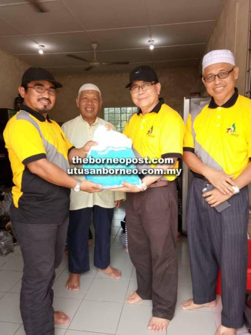  Mohamad (dua kanan) menyerahkan bungkusan kelupis untuk surau berdekatan. (Gambar kiri)