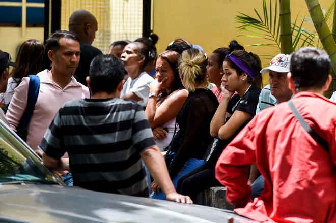  Saudara-mara mangsa rempuhan di kelab Los Cotorros, di mana kanister gas pemedih mata diletupkan di dalamnya, menunggu dalam keadaan sugul di luar rumah mayat   di Caracas, Venezuela kelmarin. — Gambar AFP