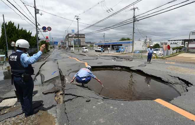  Polis memeriksa lubang besar di atas jalan raya selepas gempa bumi melanda Takatsuki, di utara wilayah Osaka di Jepun semalam. — Gambar Jiji Press/AFP