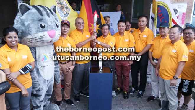  Pengerusi Majlis Daerah Marudi Edward Mendai (lima kiri) mewakili pasukan Larian Obor di Mulu, menyerahkan obor kepada Yii, sambil disaksikan yang lain. 