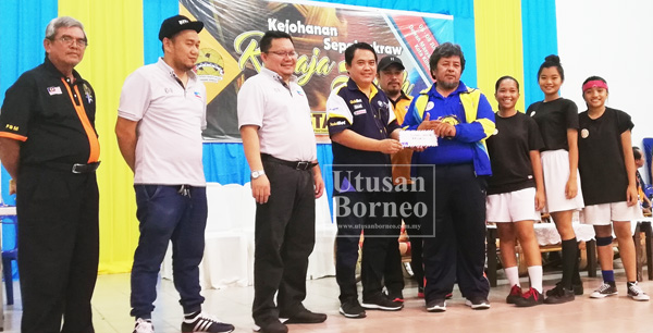 PENGURUS pasukan juara wanita Nabawan A, Awang Agindok bersama pemainnya menerima hadiah daripada Karim (empat dari kiri).