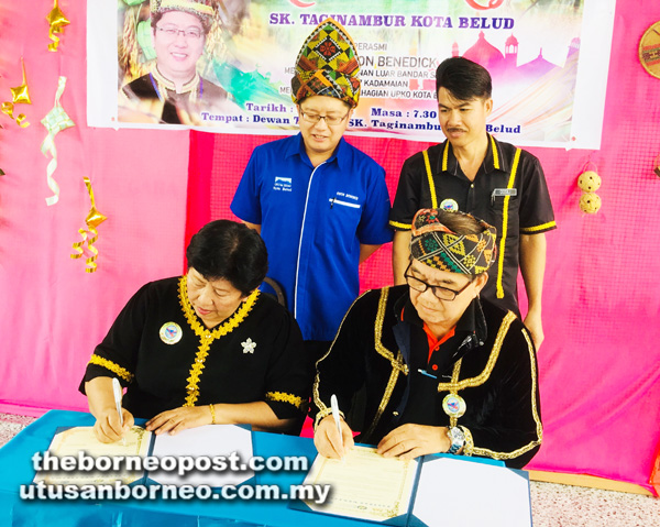 EWON (kiri) menyaksikan acara menandatangani persefahaman antara SK Taginambur yang diwakili Betty (duduk kiri) dan Simbih.
